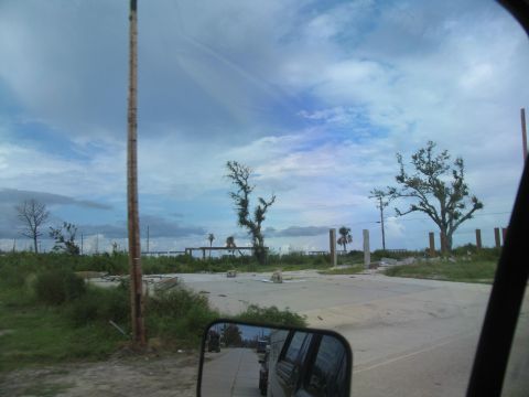 1995 Ford C-350 (Centurion Conversions) - Reflection in the side mirror shows vehicles on a road amidst the aftermath of destruction.