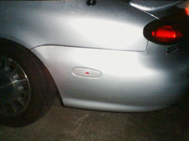 Silver car's rear quarter panel showing the taillight and side marker light