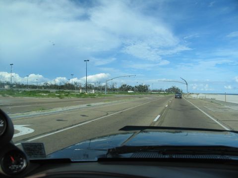 1995 Ford C-350 (Centurion Conversions) - A road scene shows the aftermath of a storm with debris and damaged infrastructure visible.