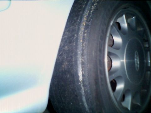 1998 Ford Taurus - A close-up shot focuses on a worn tire and a silver alloy wheel, showing signs of wear and tear.