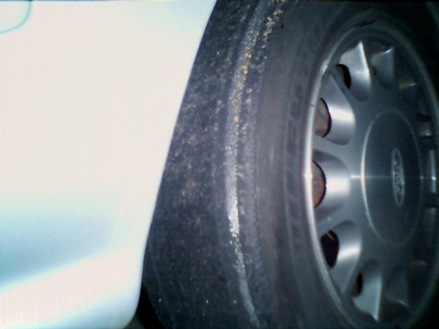 Close-up of a worn tire and a silver alloy wheel on a car