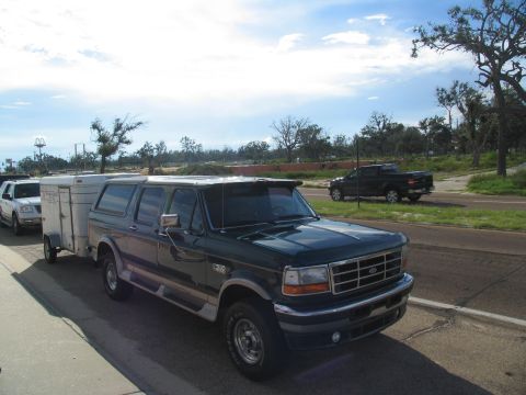 1995 Ford C-350 (Centurion Conversions) - A 1995 Ford C-350 Centurion conversion van is seen towing a trailer on a road, with another vehicle in the background.