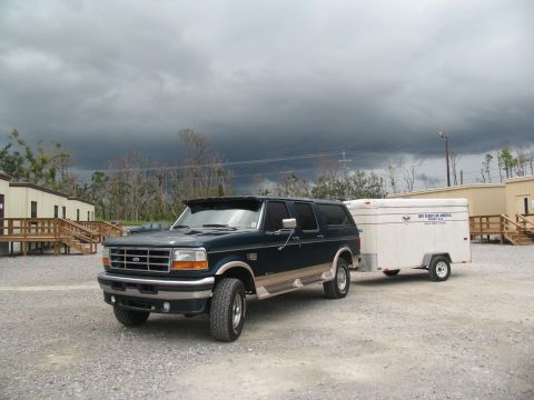 1995 Ford C-350 (Centurion Conversions) - A 1995 Ford C-350 Centurion Conversions SUV tows a trailer under a stormy sky, possibly for disaster relief efforts.