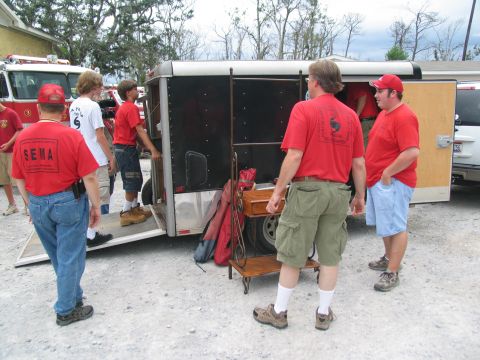 1995 Ford C-350 (Centurion Conversions) - Emergency personnel in red shirts are seen unloading a trailer, with a fire truck visible in the background.
