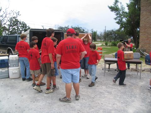 1995 Ford C-350 (Centurion Conversions) - People in red SEMA shirts are gathered outdoors, with a trailer and a cameraman visible.