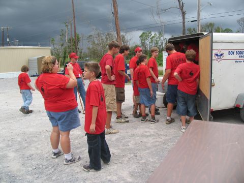 1995 Ford C-350 (Centurion Conversions) - A group of Boy Scouts in red shirts are seen unloading supplies from a trailer marked with the Boy Scouts of America logo.