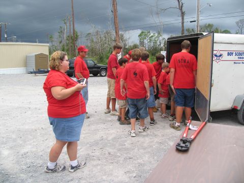 1995 Ford C-350 (Centurion Conversions) - People in red shirts gather around a trailer, with a black truck visible in the background.