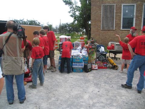 1995 Ford C-350 (Centurion Conversions) - Volunteers gather supplies for disaster relief efforts outside a building.
