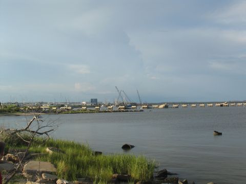 1995 Ford C-350 (Centurion Conversions) - A wide view of a bay shows a partially destroyed bridge and construction cranes, indicating ongoing repair work.
