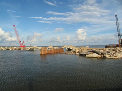 1995 Ford C-350 (Centurion Conversions) - A scene of destruction with cranes overlooking a broken bridge and scattered concrete in the water.