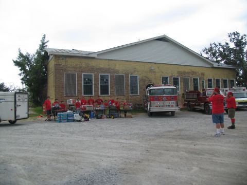 1995 Ford C-350 (Centurion Conversions) - A fire truck is parked in front of a yellow brick building with people gathered around tables.