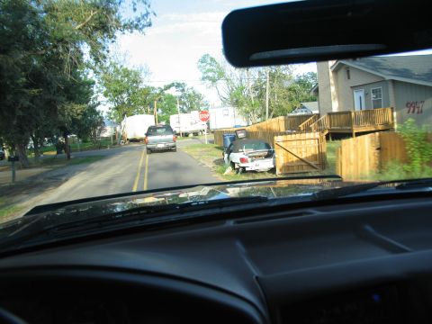 1995 Ford C-350 (Centurion Conversions) - A white convertible is parked on the side of the road next to a wooden fence and a house.