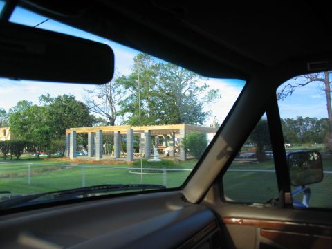 1995 Ford C-350 (Centurion Conversions) - View from inside a vehicle shows a construction site with a roof structure being built, built with concrete pillars and wooden beams.
