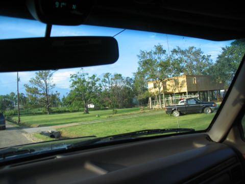 1995 Ford C-350 (Centurion Conversions) - A black pickup truck is parked on a grassy area near a house on stilts.