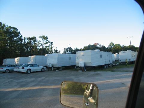 1995 Ford C-350 (Centurion Conversions) - Several white trailers and two cars are parked in a lot under a clear blue sky.