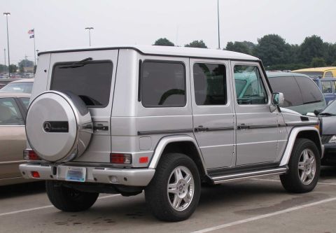 1998 Ford Crown Victoria - A silver Mercedes-Benz G-Class SUV shown from the rear three-quarter angle, featuring a rear-mounted spare tire with a Mercedes-Benz cover…