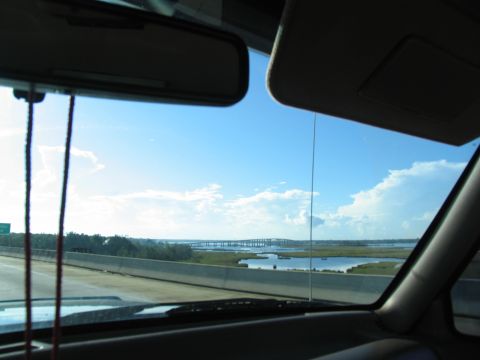 1995 Ford C-350 (Centurion Conversions) - Driving over a bridge with water and marshland visible under a bright blue sky.