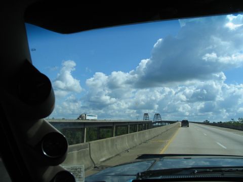 1995 Ford C-350 (Centurion Conversions) - Driving on a highway with a truck and car visible in the distance, under a bright, cloudy sky.