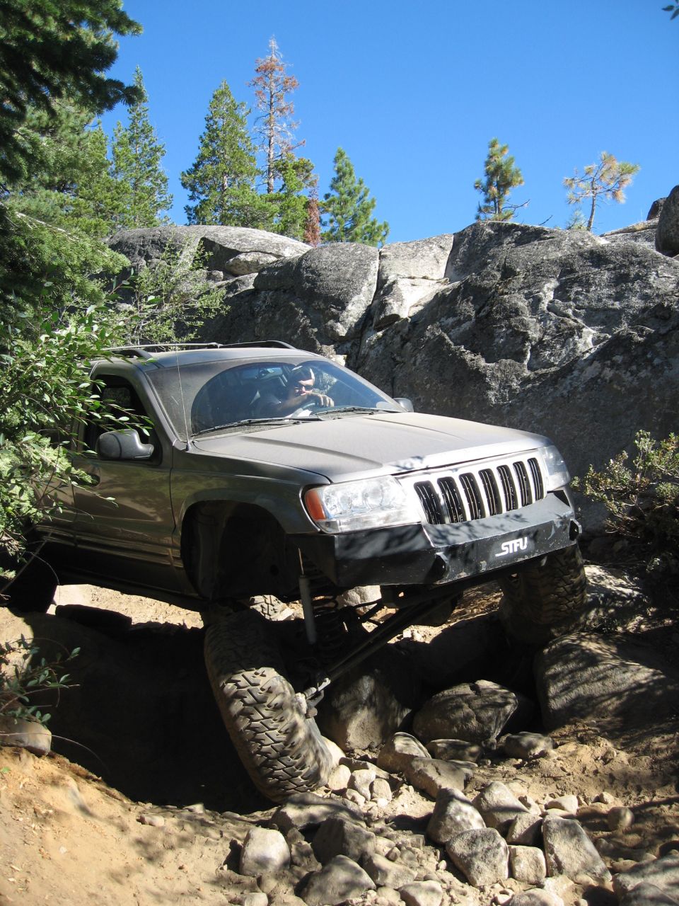 1999 Jeep Grand Cherokee navigating a steep, rocky trail with one front wheel high in the air