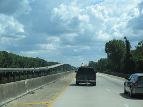 1995 Ford C-350 (Centurion Conversions) - A view from a vehicle traveling on a highway, showing an elevated bridge and other cars on the road under a cloudy sky.