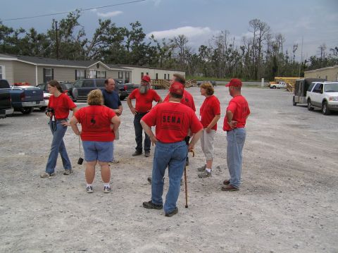 1995 Ford C-350 (Centurion Conversions) - SEMA personnel gather in a lot, with several vehicles visible in the background.