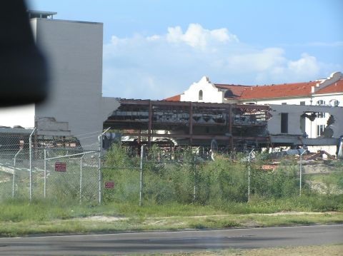 1995 Ford C-350 (Centurion Conversions) - A building shows significant damage, with its interior structure exposed and rubble scattered around.
