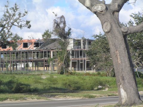 1995 Ford C-350 (Centurion Conversions) - A building in disrepair, showing exposed framing and damaged roofing, suggesting a scene of construction or post-disaster recovery.