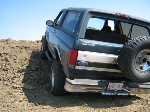 1995 Ford Bronco - Rear view of a 1995 Ford Bronco parked on a dirt hill with a spare tire on the back.