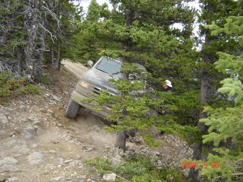 1995 Ford Bronco - Ford Bronco driving on a challenging mountain trail with dense forest cover.