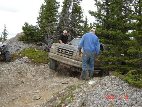 1995 Ford Bronco - A Ford Bronco is shown on a challenging off-road path, with two men observing its progress.