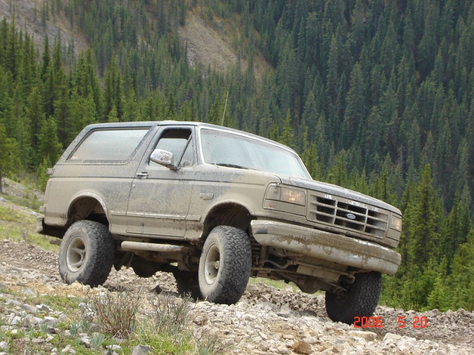 1995 Ford Bronco on a rocky trail, front 3/4 view, mud-covered