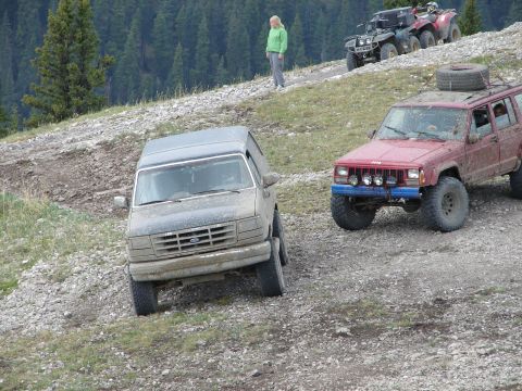 1995 Ford Bronco - A group of off-road vehicles navigate a steep, rocky incline in a mountainous area.