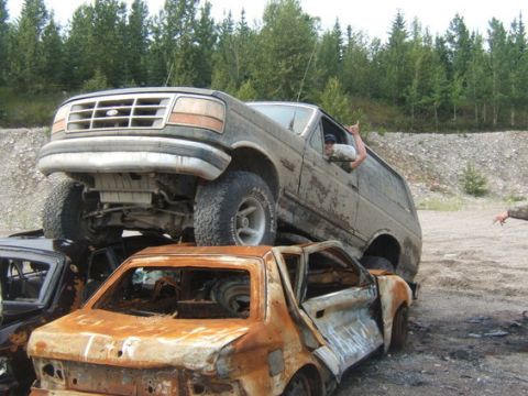 1995 Ford Bronco - This Ford Bronco is stacked on top of other vehicles in a junkyard setting.