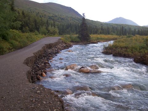 1979 Chevrolet Blazer - A scenic view of a damaged road alongside a flowing river in a mountainous, forested area.