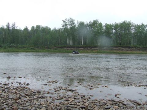 1995 Ford Bronco - SUV navigates a river crossing on a cloudy day.