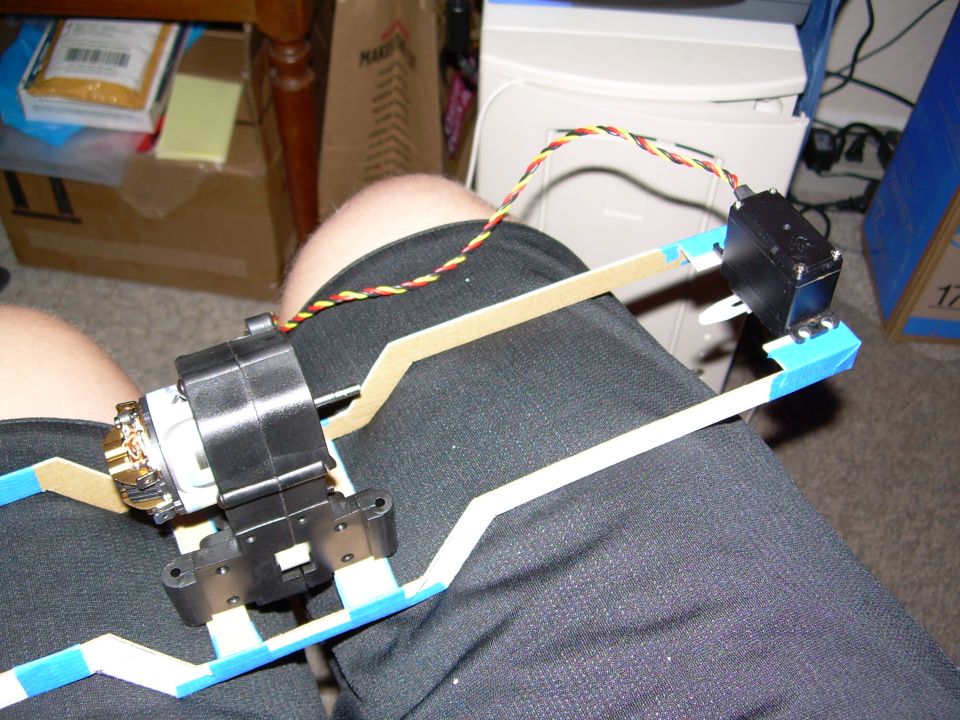 Homemade pan-tilt camera rig with servos and blue-taped arms resting on a lap