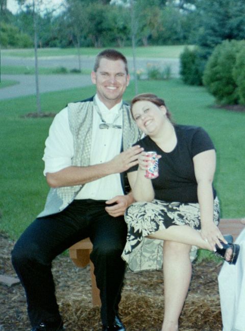 2002 Oldsmobile Aurora - A man and woman sit together on a bench, smiling for the camera on a pleasant day.
