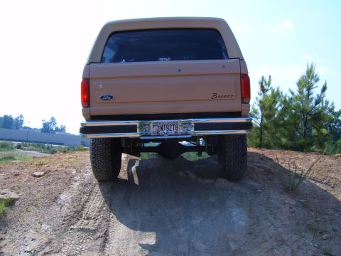 1993 Ford Bronco - Rear view of a tan 1993 Ford Bronco parked on a dirt incline.