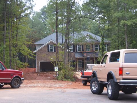 1993 Ford Bronco - A tan Ford Bronco is parked near a house under construction, with a red truck also visible.