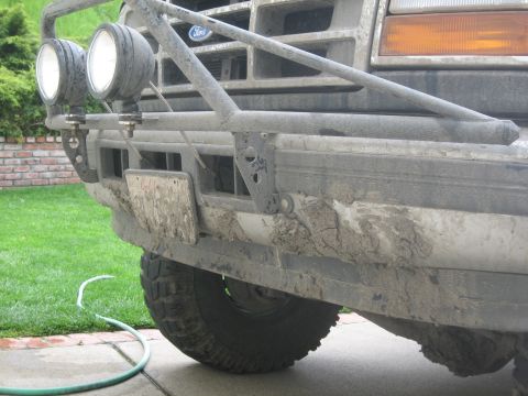 1995 Ford Bronco - Mud-caked front end of a Ford truck, likely from the early to mid-1990s, fitted with a brush guard and auxiliary lights.