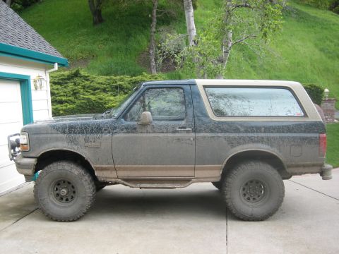 1995 Ford Bronco - This is a side view of a dirty Ford Bronco parked on a driveway.