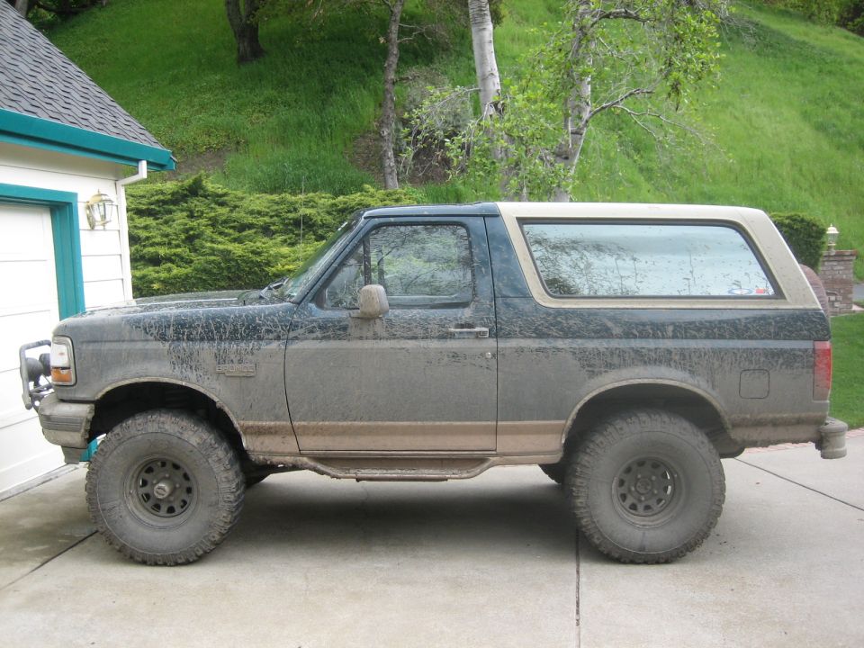 Muddy Ford Bronco parked next to a garage