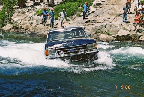 1966 Jeep CJ5 - Ford Bronco navigates a rocky river crossing, observed by onlookers.