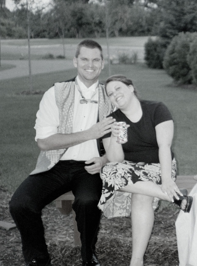 man in vest and bowtie, woman in patterned skirt, sitting on bench outdoors