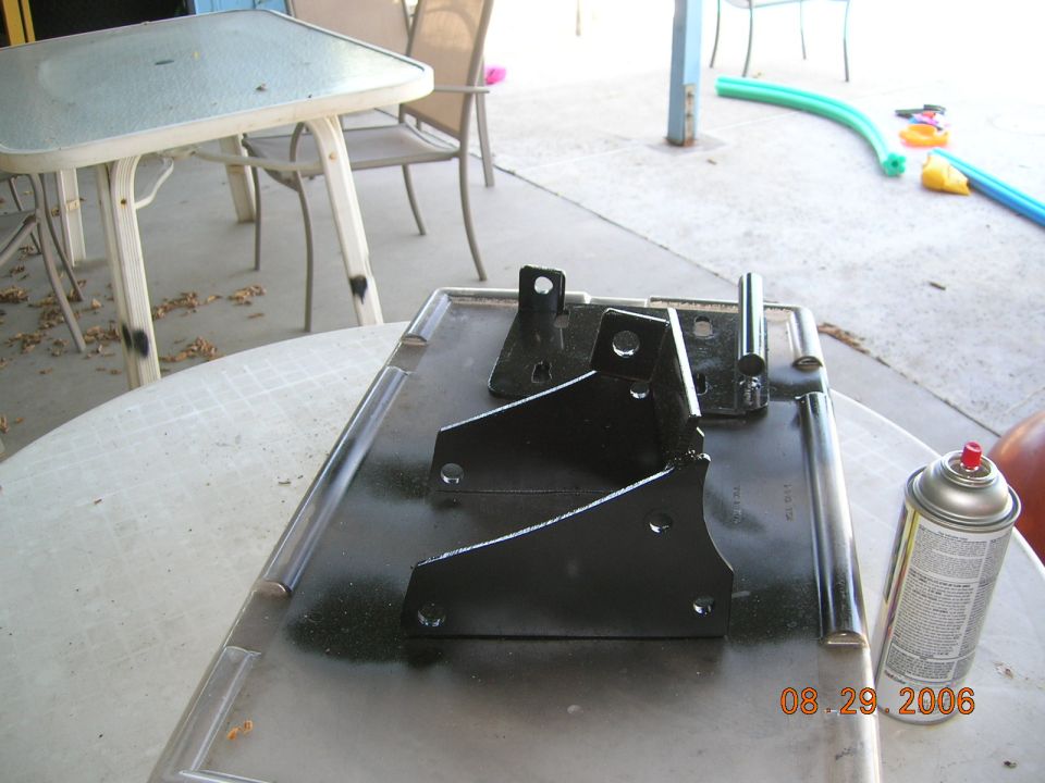 three black metal brackets on a tray with a can of spray paint next to them. Date stamp reads 08.29.2006