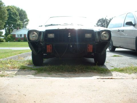 1978 Ford Mustang II - Front view of a 1978 Ford Mustang II, showing the grille and headlights, with a van in the background.