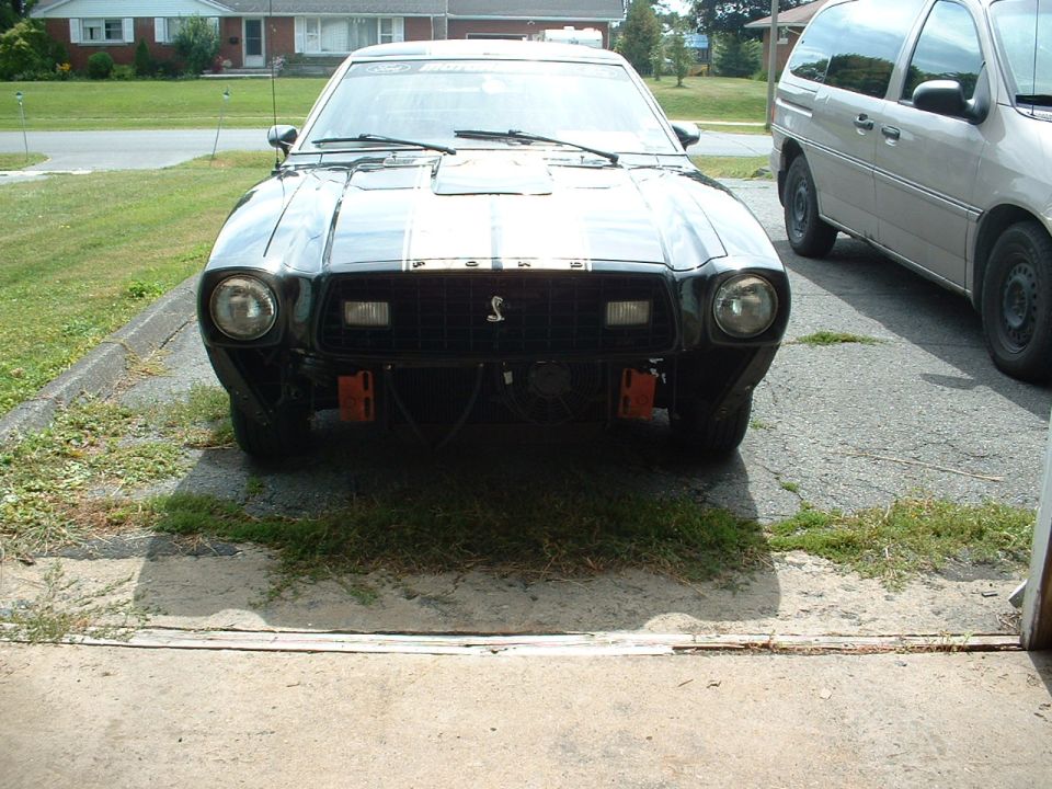 Front view of a black 1978 Ford Mustang II with racing stripes