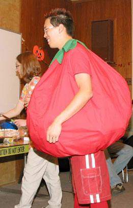 1969 Ford Mustang - A person wears a large, round red costume resembling a tomato, with green trim around the neck.