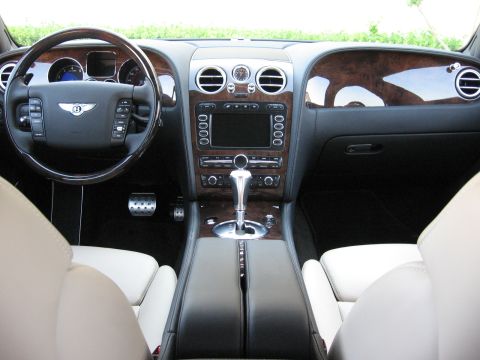 1986 Ford Bronco - The interior of a luxury vehicle features wood accents, a central infotainment screen, and plush white leather seating.