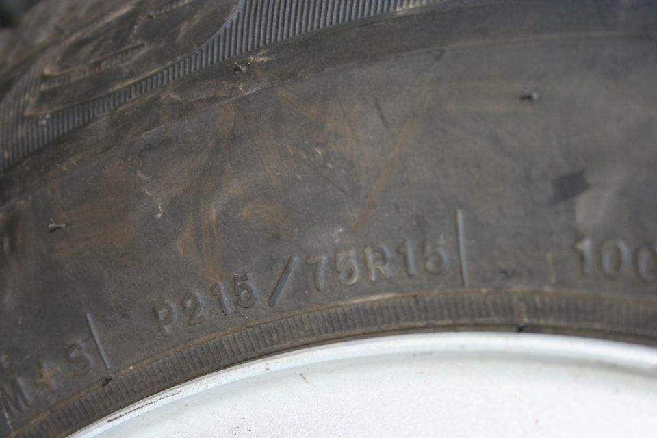 Tire sidewall shows P215/75R15 markings and a load index of 100